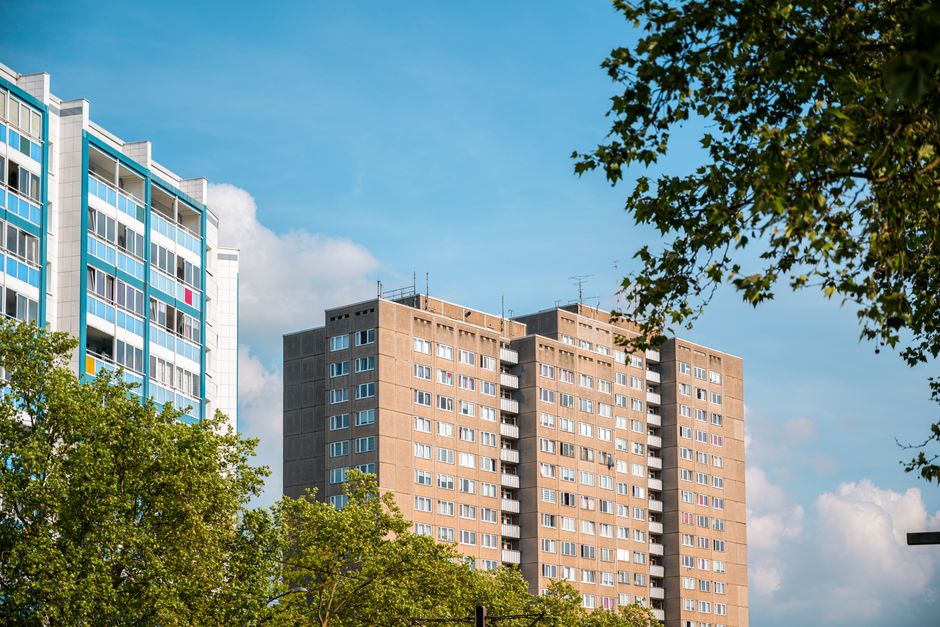 A street scene outside a residential building with a curved brick facade and multiple balconies, within which a removal team from Removals Elephant and Castle is loading furniture and boxes during a h